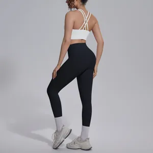 Detail of women's cross back sports bra and black yoga leggings set in studio setting.