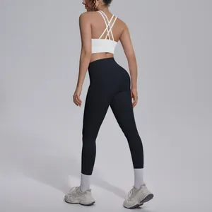 Back view of woman wearing white criss-cross sports bra and black athletic yoga leggings