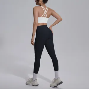 Back view of professional yoga set featuring a white cross-strap bra and black leggings