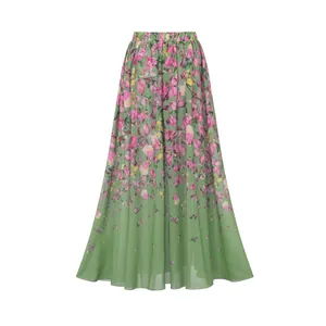 Jupe longue verte à taille haute avec imprimé floral rose vif sur un tissu en mousseline léger.