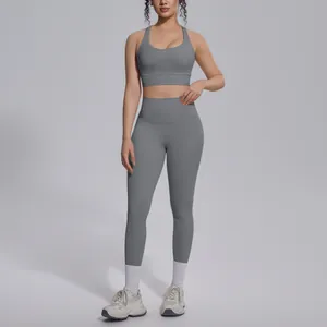 Full body shot of a model wearing a grey two-piece gym set in a studio environment.