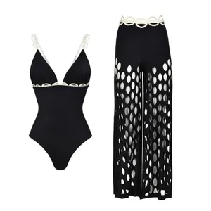 Vue détaillée d'un maillot de bain une pièce noir et d'un pantalon de plage ajouré assorti