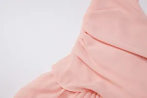Dettaglio ravvicinato che mostra le pieghe morbide e la trama leggera di un abito in chiffon rosa.