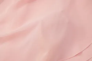 Macro dettaglio della trama del morbido tessuto chiffon rosa di un vestito estivo.