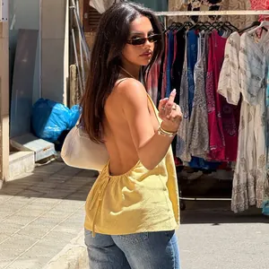 Donna elegante che indossa un top giallo con scollo all'americana in un vivace mercato