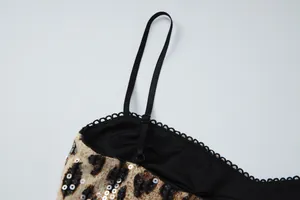 Macro detail of adjustable black strap and delicate lace trim on leopard print sequin dress.