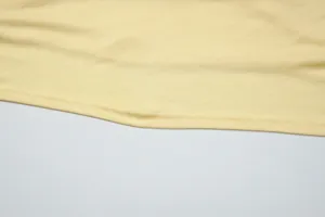 Vista macro dettagliata della trama del tessuto a maglia giallo e dell'orlo cucito