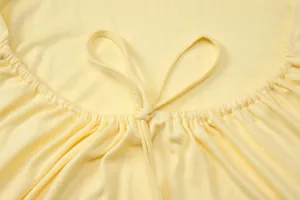 Primo piano del delicato laccio e della trama pieghettata su un top halter giallo
