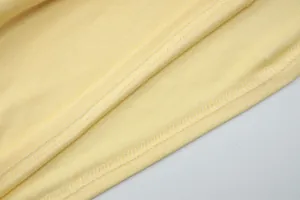 Primo piano dettagliato della cucitura overlock su un morbido tessuto di maglia giallo.