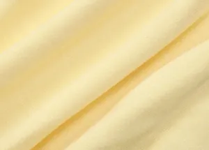 Dettaglio macro del morbido tessuto a maglia giallo pallido con texture fine e pieghe