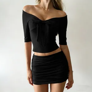 Detalle del top negro con hombros descubiertos y lazo y minifalda fruncida a juego.