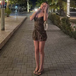 Full-length view of a woman wearing a sexy leopard print chiffon mini camisole dress at night