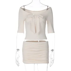 Conjunto elegante de top beige con hombros al aire y lazo con minifalda fruncida