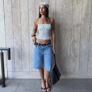 Detail view of a chic white polka dot camisole top paired with denim shorts.