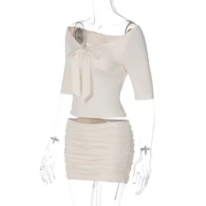 Detalle del elegante top con hombros descubiertos y lazo con falda fruncida a juego