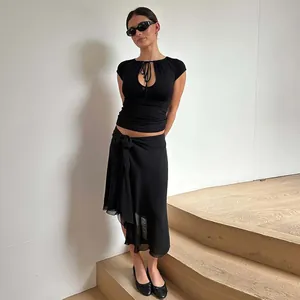 Fashionable woman wearing a black keyhole cutout tie-front T-shirt on wooden stairs