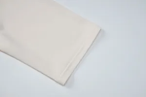 Primer plano del dobladillo de doble costura de alta calidad de un top ajustado color crema.