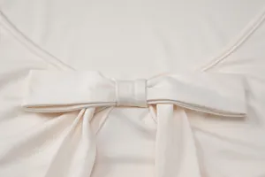 Primer plano elegante del detalle del lazo decorativo en un top de moda color crema.