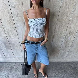 Detailed look of a stylish white polka dot sleeveless crop top paired with denim shorts