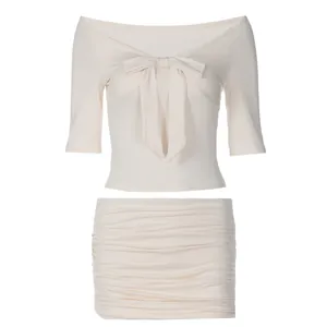 Elegante conjunto de dos piezas crema con top de hombros descubiertos y minifalda fruncida