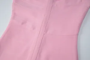 Close-up of pink bandage dress showing ribbed elastic fabric texture and vertical seams.