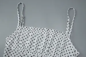 Detail shot of a white polka dot camisole top featuring a delicate ruffled neckline.