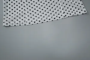 Close-up view of the fine stitching and polka dot print on a white camisole hem