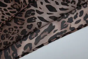 Close-up of leopard animal print chiffon fabric showing texture and hem stitching details