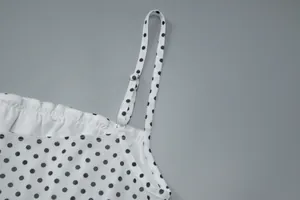 Close-up view of the adjustable strap on a white polka dot camisole with mesh fabric.