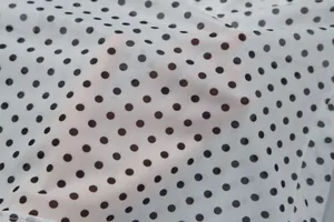 Close-up detail of the breathable white mesh fabric with classic black polka dot pattern.