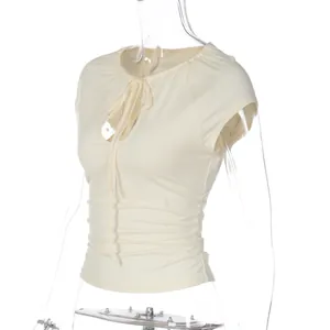Detail of light beige slim-fit top with cutout neckline and ruched waist tie design.