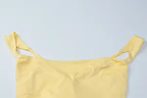 Close-up of the elegant flat neckline and strap design on a light yellow evening dress.