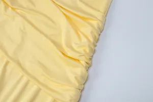 Macro view of light yellow evening dress fabric showing soft drape and fine texture