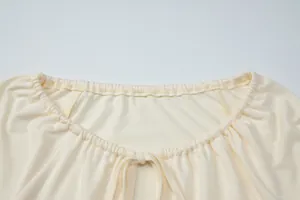 Close-up of elastic gathered neckline with drawstring and cutout detail on cream top