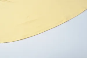 Macro shot of the double-stitched hemline on a slim-fit yellow sleeveless evening dress