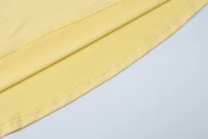 Close-up detail showing the high-quality stitching on a yellow evening dress hem.