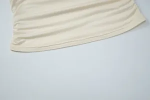 Close-up of ruched waist detail on cream-colored slim fit T-shirt top