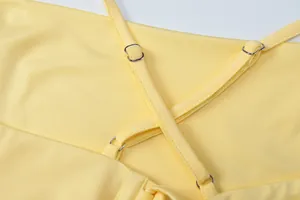 Detailed close-up of yellow dress showing adjustable cross-back straps and metal buckles