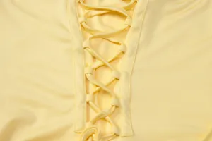 Close-up of the elegant lace-up crisscross back detail on a pale yellow evening dress