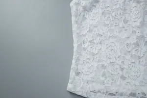 Detailed macro view showing the intricate floral pattern of the white lace fabric texture