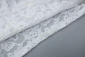 Macro close-up detail of white floral lace fabric with subtle sparkling sequin embellishments