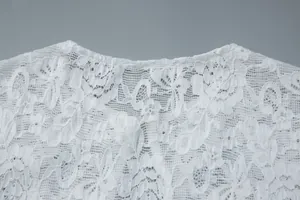 Close-up detail of white floral lace fabric with subtle sequin embellishments.