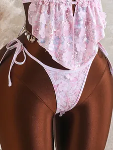 Detailopname van een roze bloemenbikini met pailletten en 3D-bloemenapplicaties