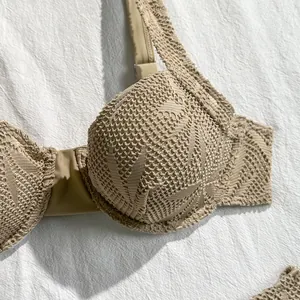 Detailed macro shot of beige crochet lace hollow bikini top featuring underwire cups