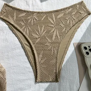 Detailed macro view of beige crochet lace bikini bottom featuring intricate leaf patterns