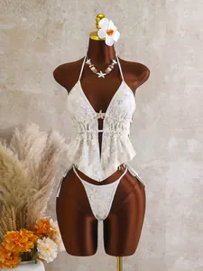 Witte tweedelige bikini met bloemen en pailletten op een paspop met zomerse decoratie.