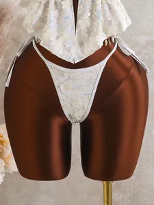 Detailopname van een witte tweedelige bikini met bloemen en lovertjes op een bruine etalagepop.
