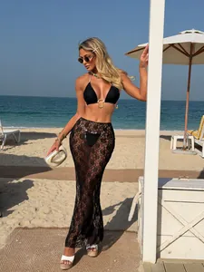 Elegant black lace mesh three-piece bikini swimsuit set with a long skirt in beach setting