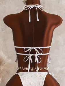 Detailweergave van sexy bloemenbikini met halternek en tailleketting met schelphangers.
