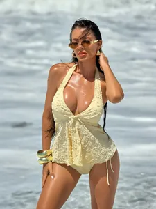 Detailed view of yellow floral textured tankini swimsuit on model at the beach.